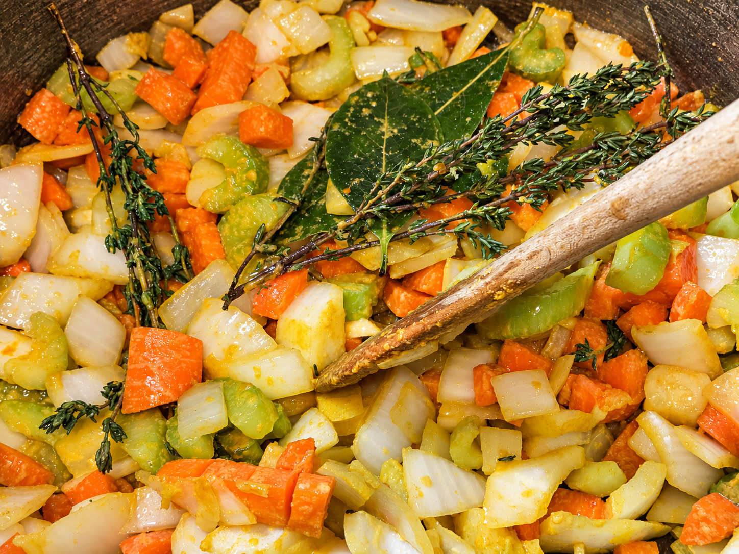 Carrots, celery, onion, garlic, bay leaves, and thyme sautéing in a pot