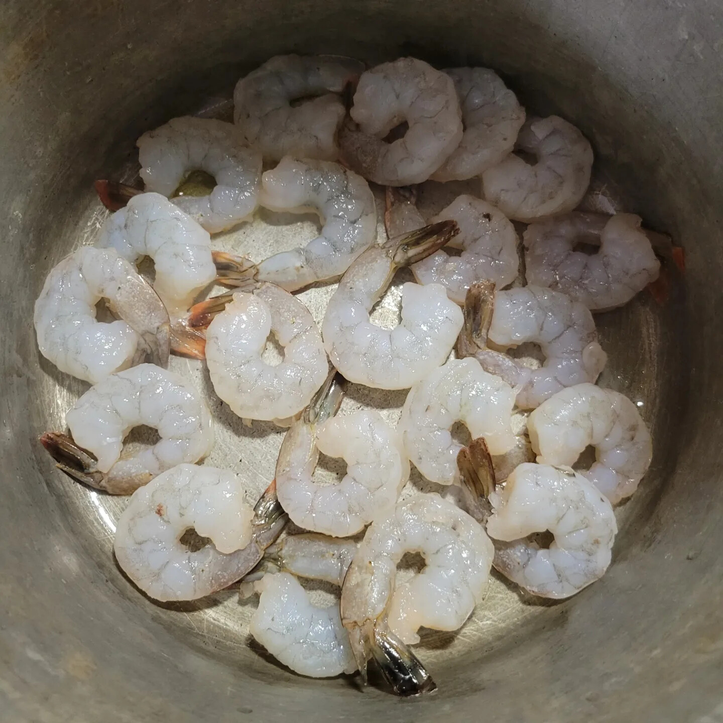 Raw peeled and deveined shrimp arranged in a metal pot