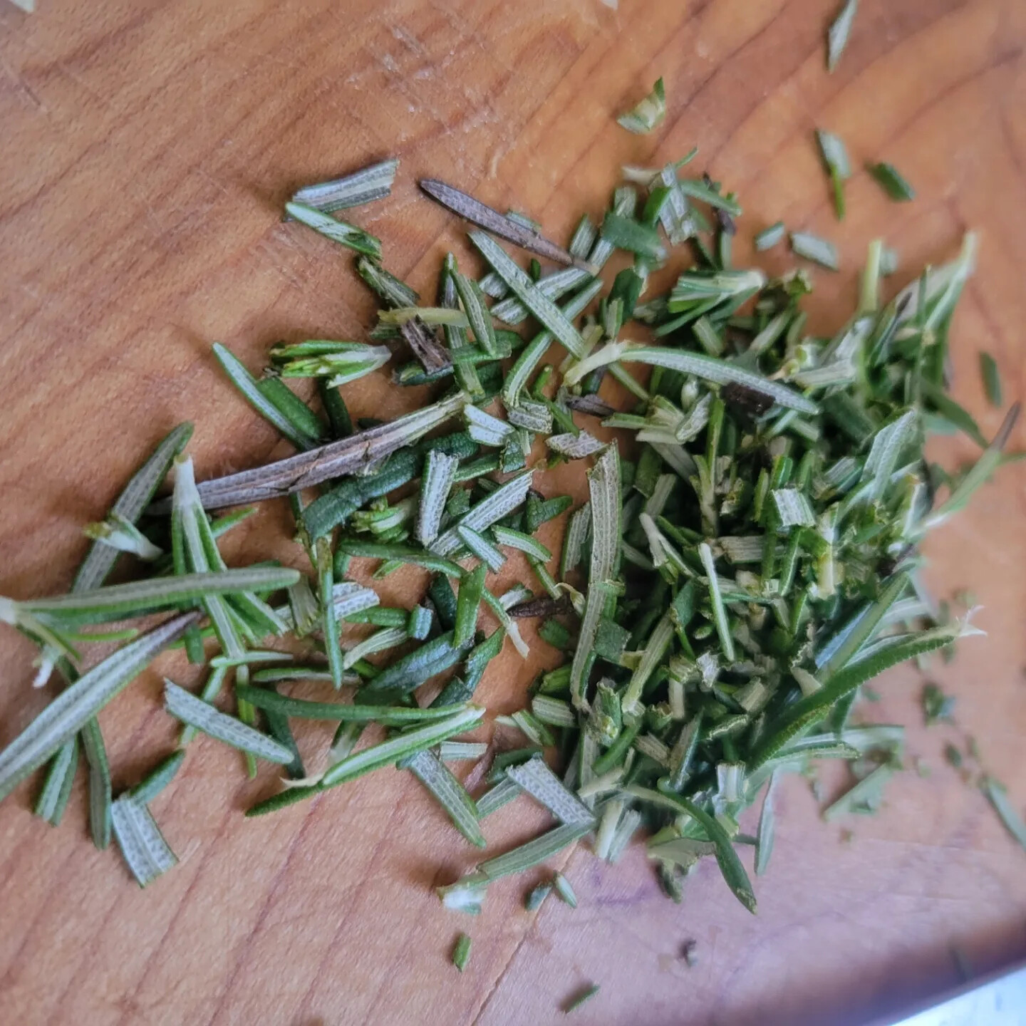 Fresh rosemary chopped on a wooden cutting board