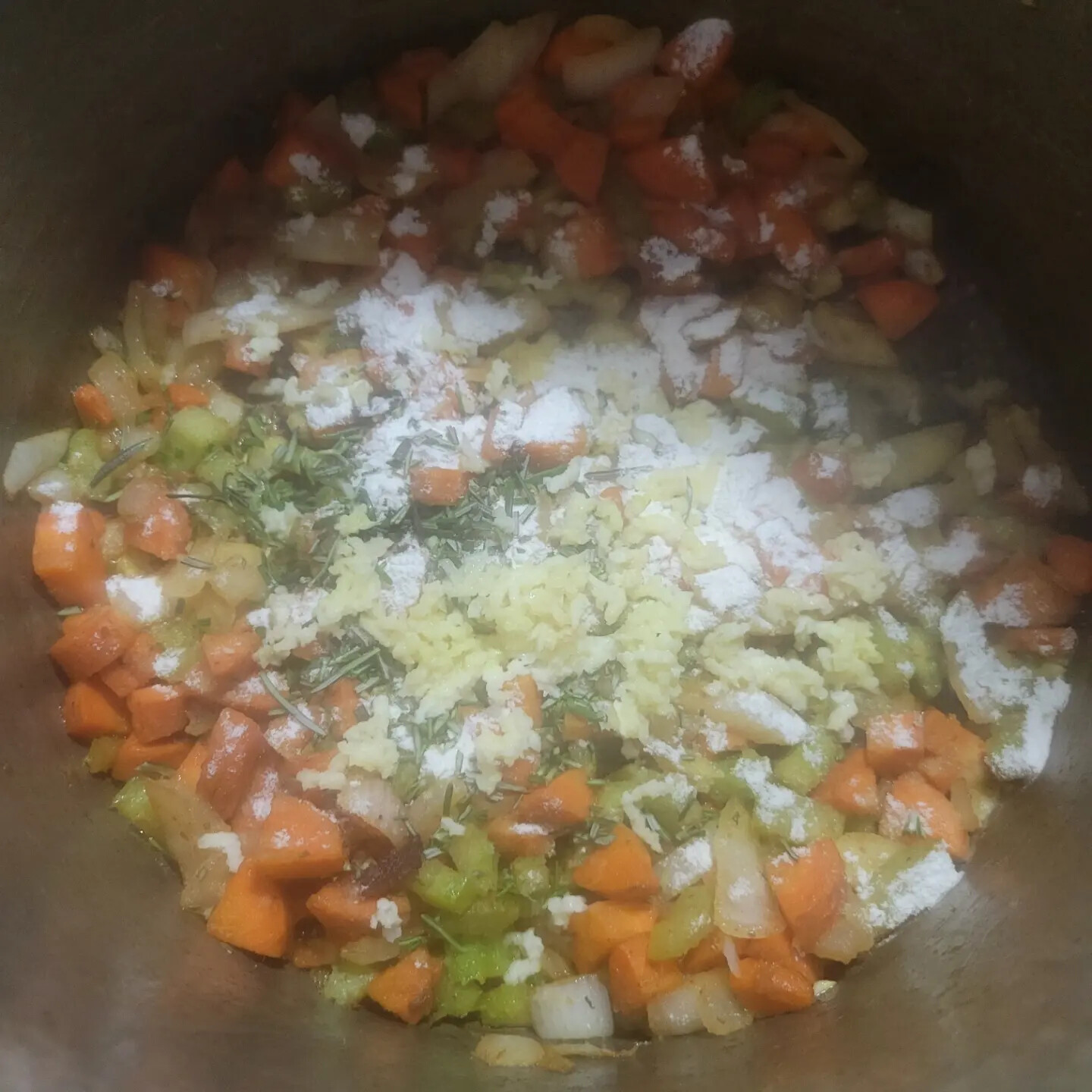 Softened vegetables with minced garlic, rosemary, and flour in a pot