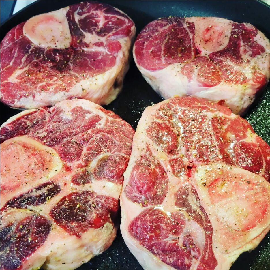Seasoned beef shanks beginning to brown in a dark Dutch oven