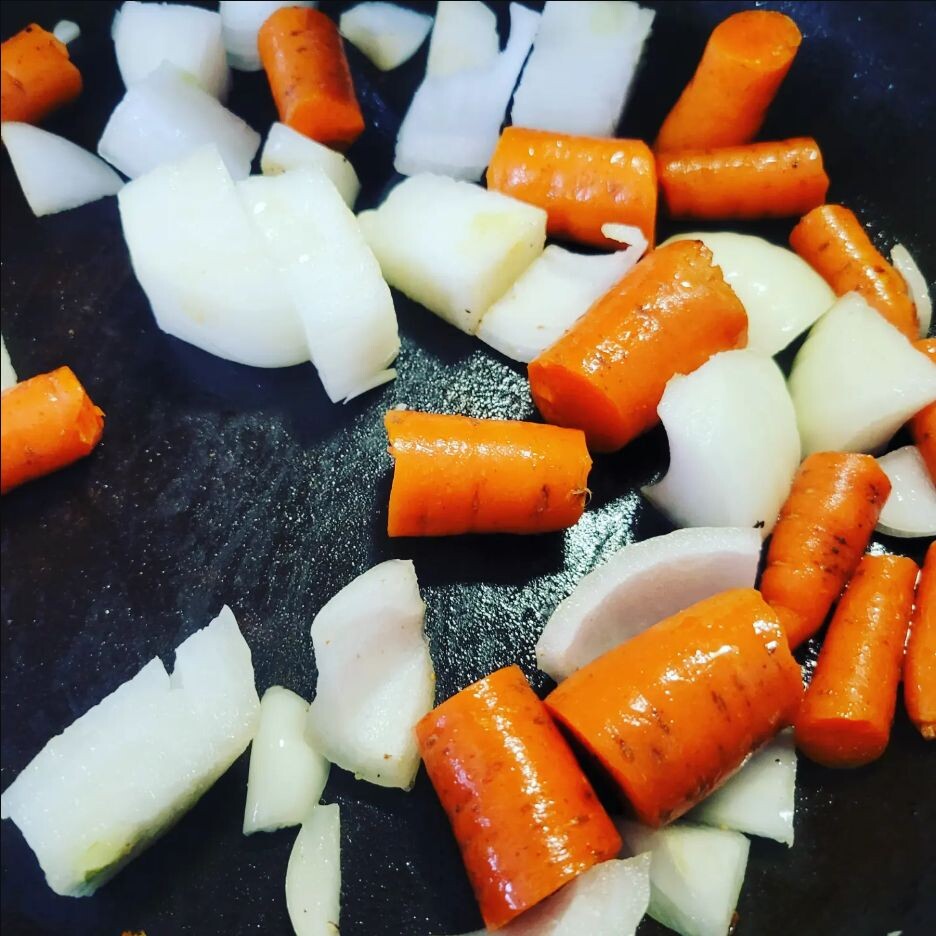 Chopped onions and carrots cooking in the Dutch oven