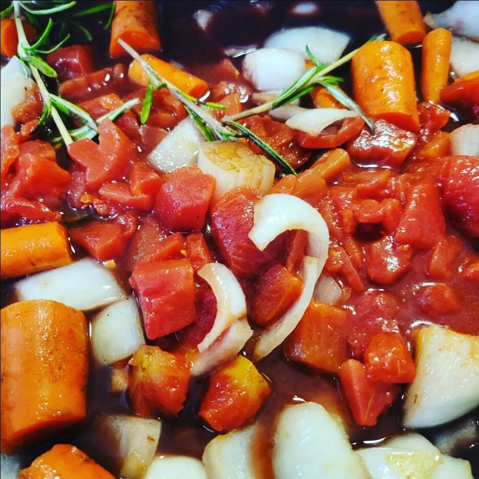 Tomatoes, red wine, onions, carrots, and rosemary in the Dutch oven